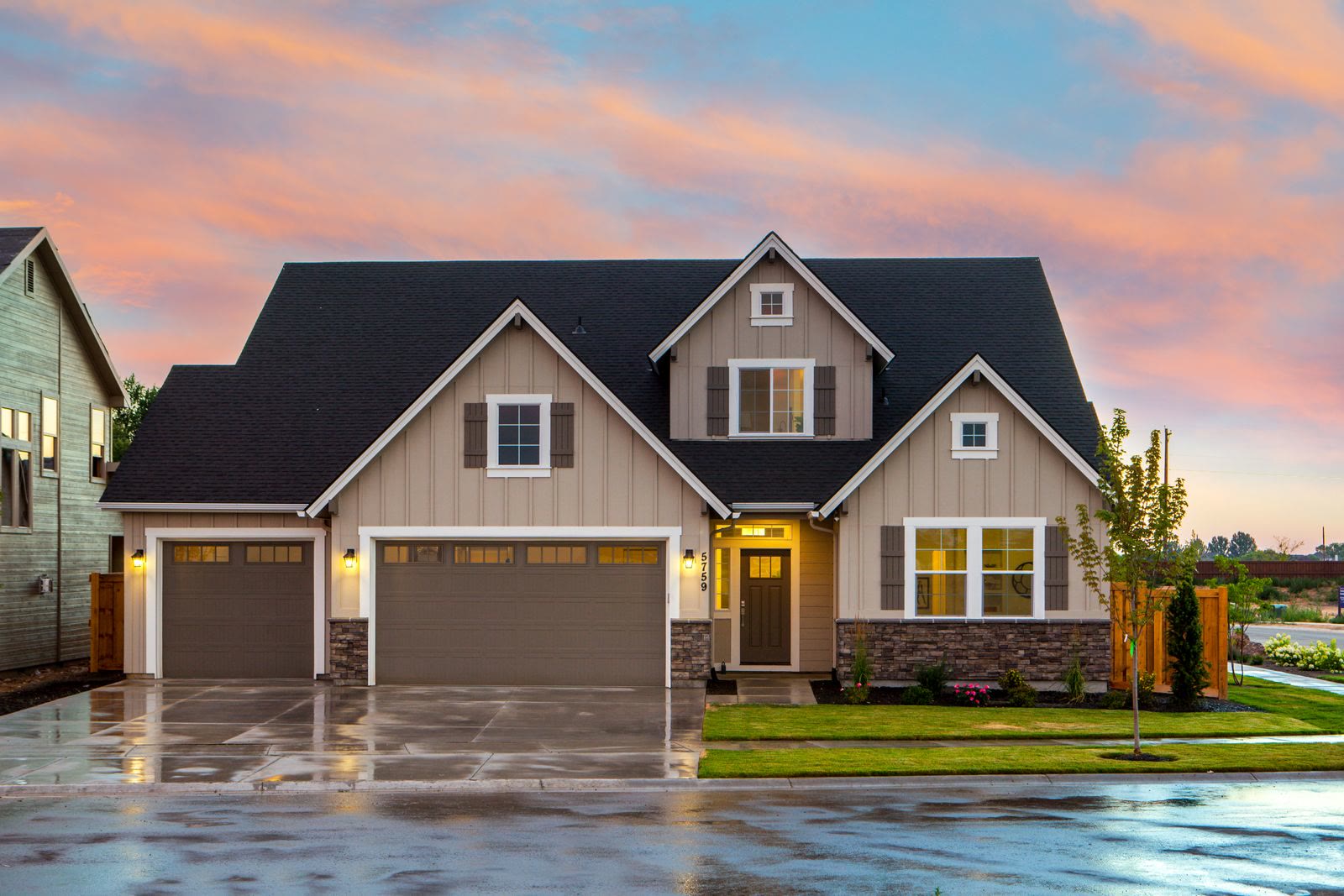 Board-and-batten modern farmhouse suburban home with stone veneer and dark roof representing Gilbert