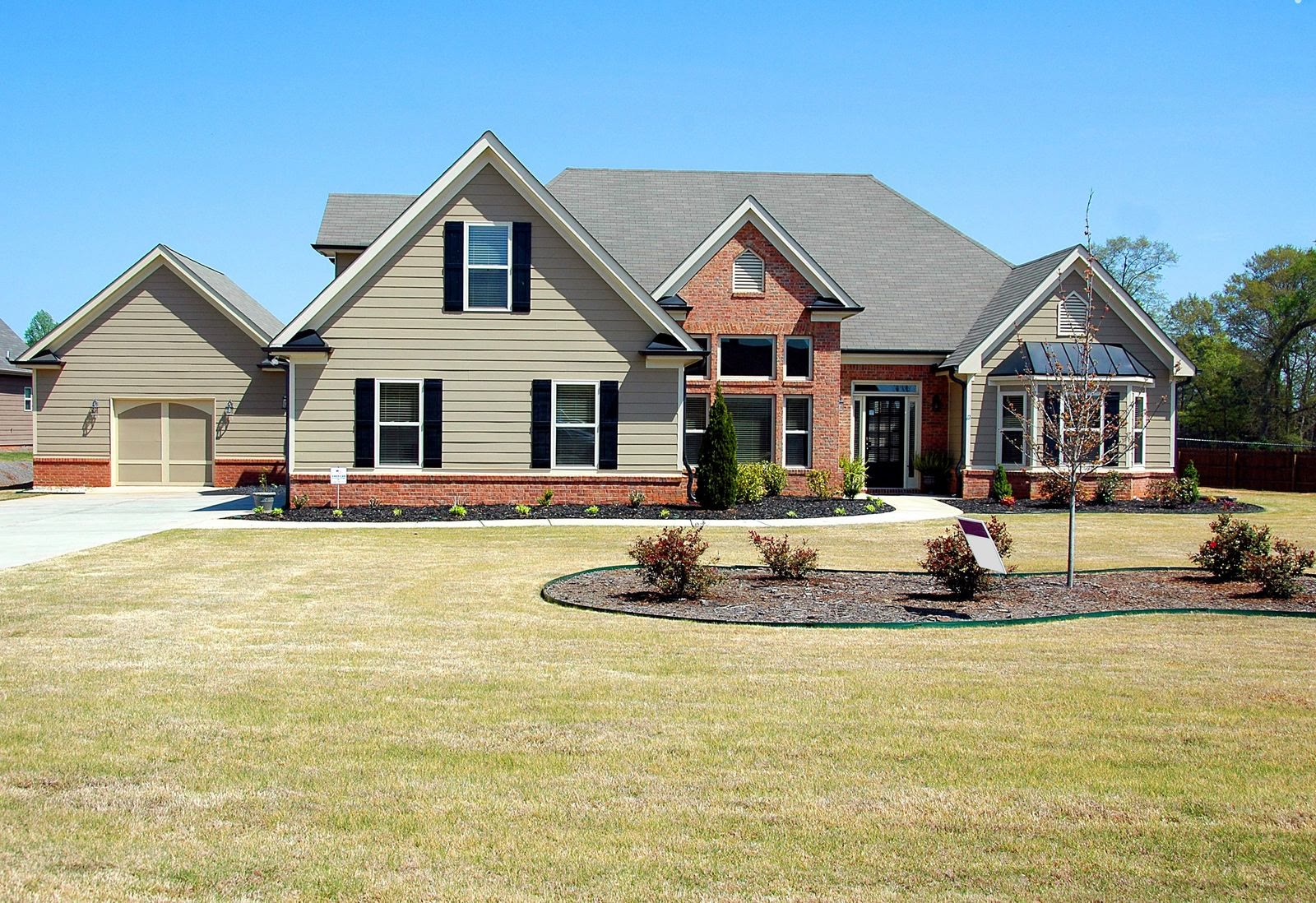 Tan siding neo-eclectic farmhouse-style suburban home with brick accents and dark roof representing Mesa