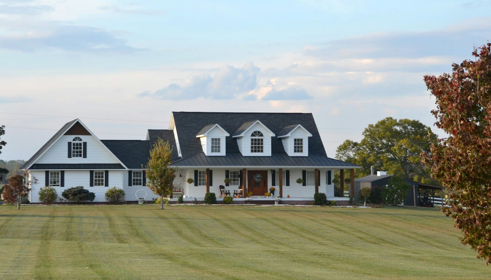 White modern farmhouse with wrap-around porch, wood columns, and dark roof representing Paradise Valley