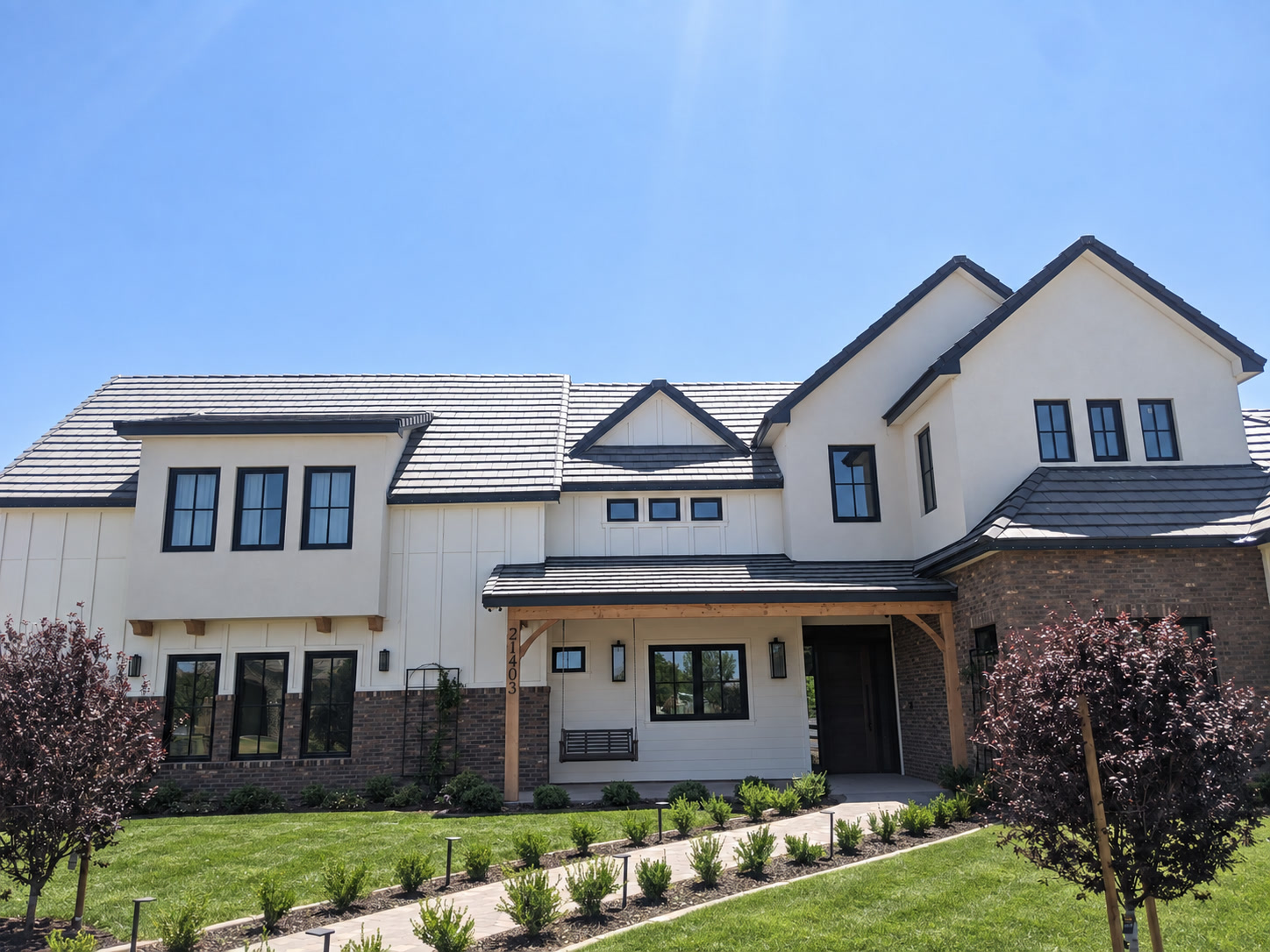 Modern farmhouse AZ-style suburban home with white board-and-batten, brick veneer base, charcoal tile roof, and manicured lawn